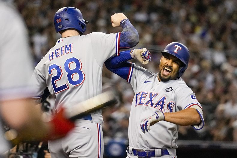 Marcus Semien (derecha) festeja su jonrón de tres carreras junto a Jonah Heim, su compañero en los Rangers de Texas, en el cuarto juego de la Serie Mundial ante los Diamondbacks de Arizona, el martes 31 de octubre de 2023 (AP Foto/Brynn Anderson)