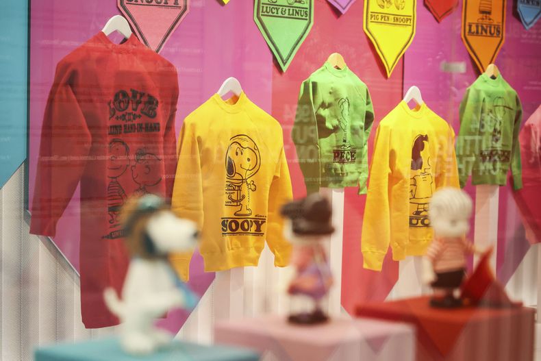 Camisetas y sudaderas impresas con los personajes de Snoopy se exhiben como parte del 75.° aniversario de Peanuts, en la exposición Snoopy In Style en París el jueves 20 de marzo de 2025. (Foto AP/Thomas Padilla)