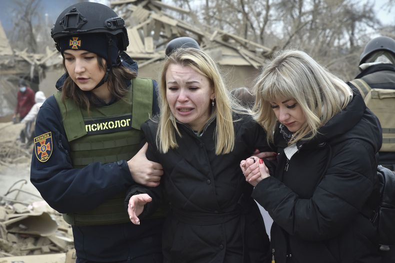 Una psicóloga de los servicios de emergencias (izquierda), consuela a una mujer en el escenario de un ataque aéreo ruso, en Zaporiyia, Ucrania, el 22 de marzo de 2024. (AP Foto/Andriy Andriyenko)
