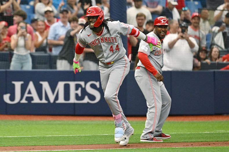 Elly de la Cruz (44), de los Rojos de Cincinnati, y el entrenador de tercera base Willie Harris celebran el jonrón de dos carreras de De la Cruz durante la primera entrada de un partido de béisbol contra los Rays de Tampa Bay el martes 21 de abril de 2026, en St. Petersburg, Florida. (AP Foto/Jason Behnken)