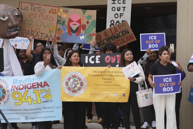 Manifestantes levantan carteles contra redadas migratorias el jueves 12 de junio de 2025 en Ventura, California. (AP Foto/Damian Dovarganes)
