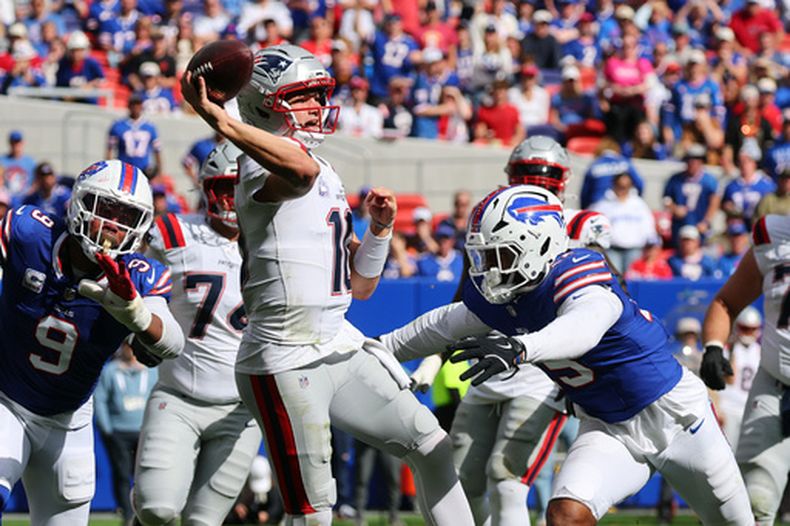 El mariscal de campo de los Patriots de Nueva Inglaterra, Drake Maye (10), lanza un pase bajo la presión del apoyador de los Bills de Búfalo, Greg Rousseau (15), durante la segunda mitad de un partido de fútbol americano de la NFL en Orchard Park, Nueva York, el 4 de octubre de 2026. (Foto AP/Jeffrey T. Barnes)