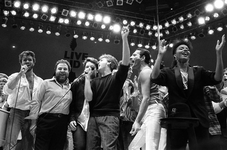 ARCHIVO - George Michael, de izquierda a derecha, el promotor de conciertos Harvey Goldsmith, Bono, Paul McCartney, Bob Geldof y Freddie Mercury aparecen durante el concierto de ayuda contra la hambruna London Live Aid en Londres el 13 de julio de 1985. (Foto AP/Joe Schaber, archivo)