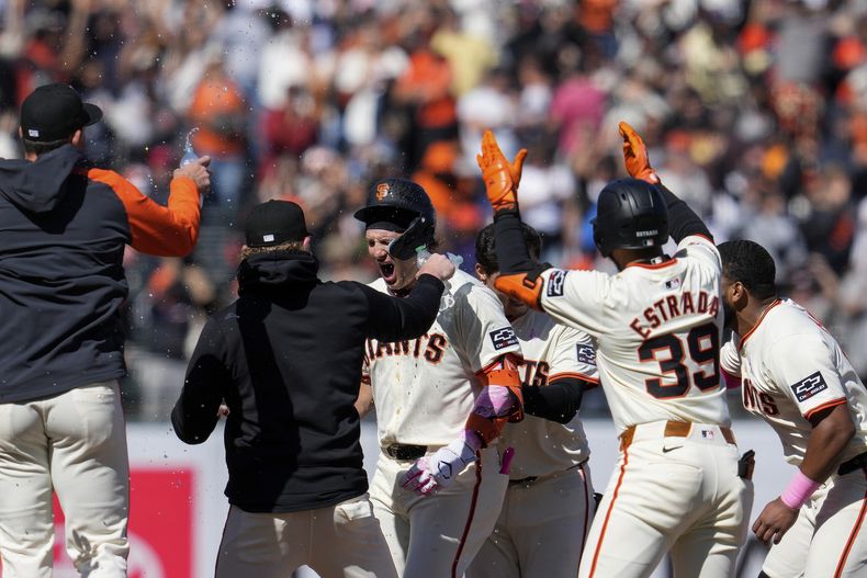 Casey Schmitt, centro, de los Gigantes de San Francisco, es felicitado por sus compañeros de equipo después de conectar un doble por regla para la victoria sobre los Rojos de Cincinnati en la 10ma entrada del juego de béisbol del domingo 12 de mayo de 2024, en San Francisco. (AP Foto/Godofredo A. Vásquez)
