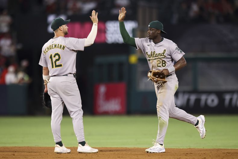 El campocorto de los Atléticos de Oakland, Max Schuemann (12), y el jardinero Daz Cameron (28), celebran después de derrotar a los Angelinos de Los Ángeles en Anaheim, California, el sábado 27 de julio de 2024. (AP Foto/Jessie Alcheh)