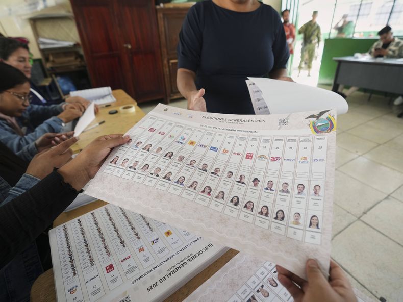 Una funcionaria electoral entrega una papeleta a un votante durante las elecciones presidenciales en Quito, Ecuador, el domingo 9 de febrero de 2025. (Foto AP/Dolores Ochoa)