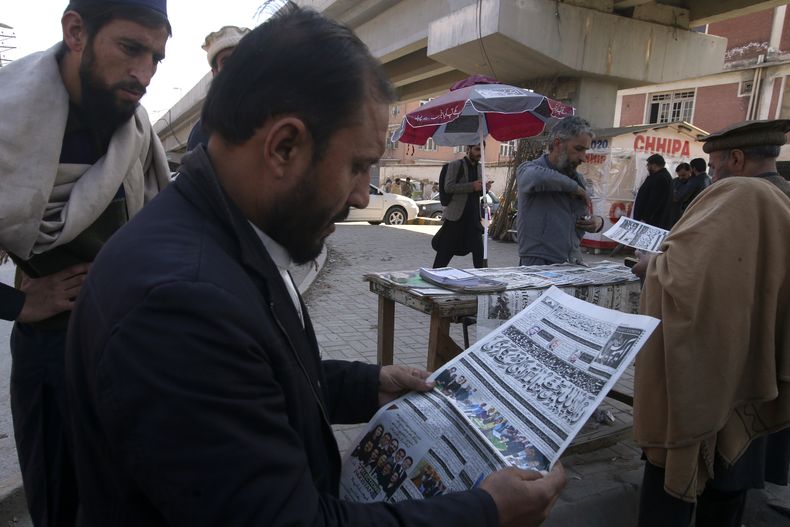 Varias personas leen en el diario el reporte de los primeros resultados de las elecciones parlamentarias, en Peshawar, Pakistán, el 9 de febrero de 2024. (AP Foto/Muhammad Sajjad)