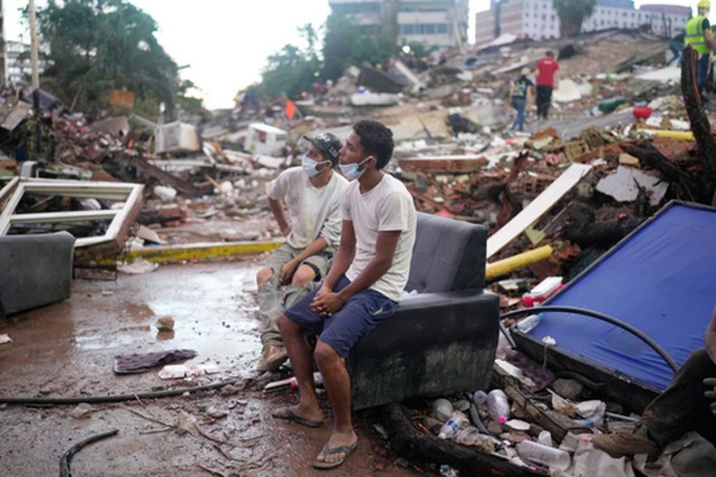 Residentes que ayudan en las labores de rescate se sientan entre escombros que dejaron los terremotos en La Guaira, Venezuela, el 30 de junio de 2026. (Foto AP/Ariana Cubillos)
