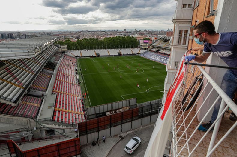 Un hombre en un balcón observa el partido de la segunda división entre el Rayo Vallecano y el Albacete en Madrid, España, el 10 de junio de 2020. (Foto AP/Manu Fernández, Archivo)