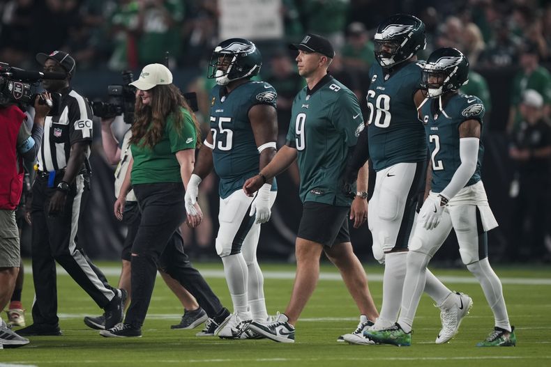 El ex Eagle de Philadelphia, Nick Foles (tercero desde la derecha), camina junto a Brandon Graham (desde la izquierda), Jordan Mailata, y Darius Slay Jr., todos de los Eagles de Philadelphia, mientras se rinde homenaje al retiro de Foles previo al juego de NFL ante los Falcons de Atlanta, el lunes 16 de septiembre de 2024, en Filadelfia. (AP Foto/Matt Rourke)