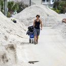 David DeMeza camina con sus pertenencias entre calles cubiertas de arena arrastrada por el huracán Helene, el 2 de octubre de 2024, en Treasure Island, Florida (AP Foto/Mike Carlson)