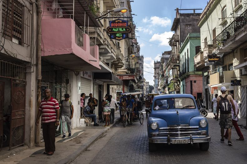 ARCHIVO - La gente camina bajo un cartel que anuncia una tienda de comestibles privada, a la izquierda, en La Habana, Cuba, el 11 de noviembre de 2023. El gobierno cubano anunció el 4 de marzo de 2024 que recibió apoyo del Programa Mundial de Alimentos para comprar leche en polvo. (AP Foto/Ramón Espinosa, Archivo)
