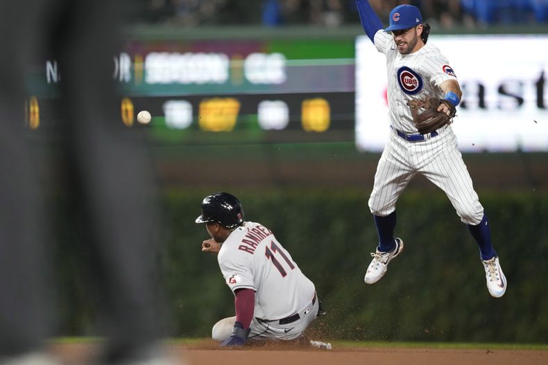 El dominicano José Ramírez, de los Guardianes de Cleveland, se barre en la intermedia sin que el torpedero de los Cachorros de Chicago, Dansby Swanson, a la derecha, logre controlar un lanzamiento del segunda base Nico Hoerner en la sexta entrada del partido en Chicago, el sábado 1 de julio de 2023. (AP Foto/Charles Rex Arbogast)