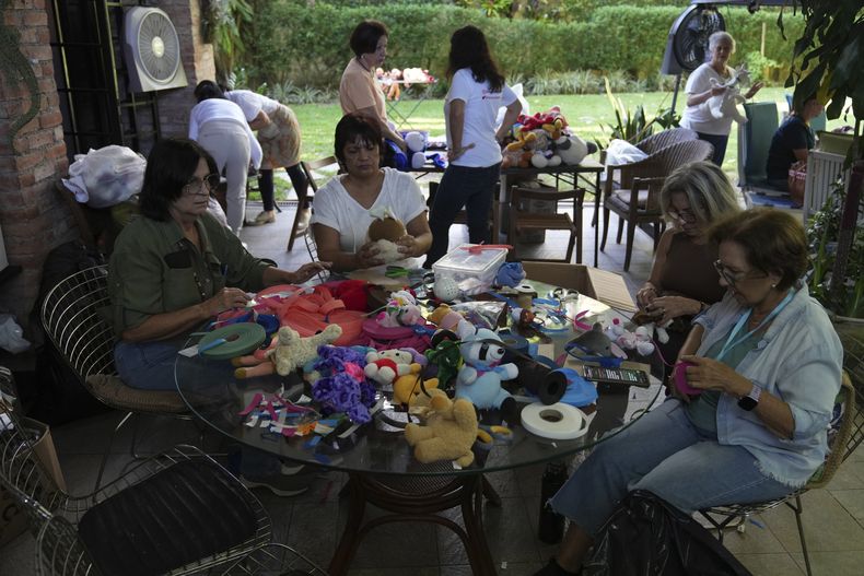 Varias voluntarias reparan juguetes usados para donarlos a niños vulnerables como regalos de Navidad, en la organización sin fines de lucro Hospital de los Peluches, en Caracas, Venezuela, el jueves 5 de diciembre de 2024. (AP Foto/Ariana Cubillos)