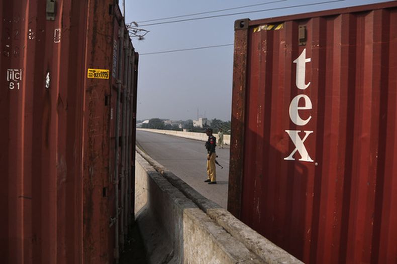 Un policía monta guardia en una carretera cortada con contenedores de mercancías antes de una protesta de partidarios del encarcelado ex primer ministro Imran Khan para exigir su liberación, en Peshawar, Pakistán, el domingo 11 de octubre de 2026. (AP Foto/Mohammad Zubair)