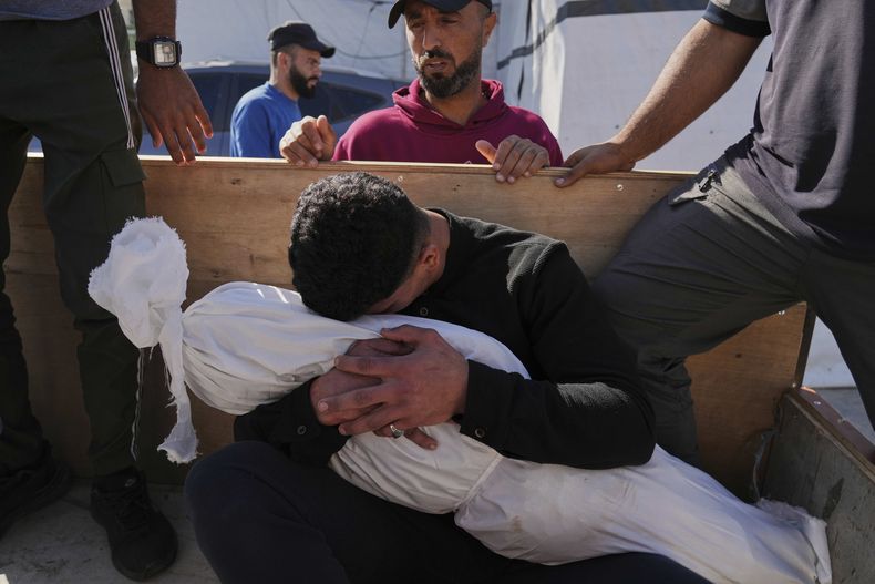 Un palestino abraza el cuerpo de su hijo de 5 años, Adam Namrouti, que murió en un ataque nocturno israelí contra una escuela de la ONU usada como refugio, antes de su entierro en el hospital Al-Aqsa, en Deir al-Balah, en el centro de la Franja de Gaza, el miércoles 7 de mayo de 2025. (AP Foto/Abdel Kareem Hana)