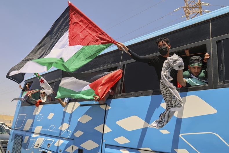 Miembros de una caravana humanitaria de al menos 1.500 personas, incluidos activistas y partidarios de Argelia y Túnez, ondean banderas palestinas desde un autobús mientras el grupo viaja hacia Gaza, en una ruta al cruce de Rafah en Egipto, en Zawiya, Libia, el martes 10 de junio de 2025. (AP Foto/Yousef Murad)