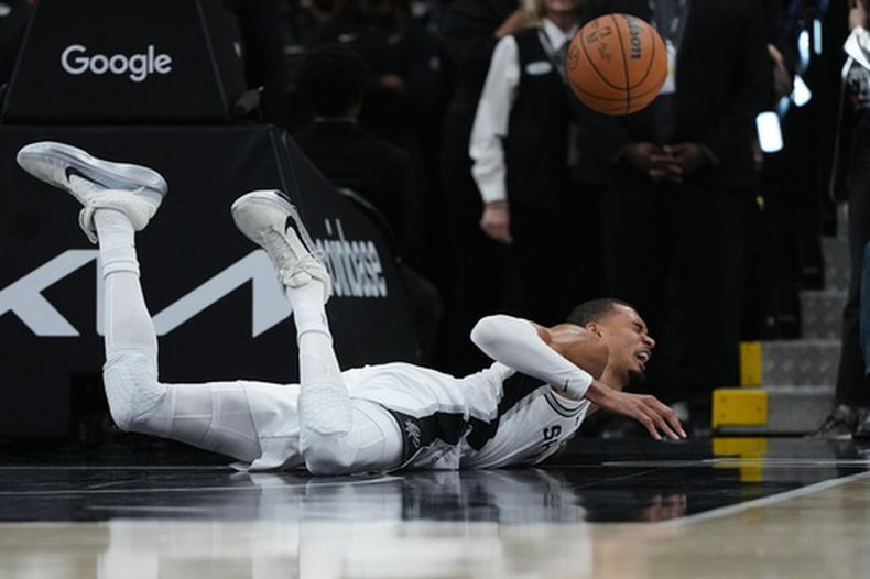El delantero de los Spurs de San Antonio, Victor Wembanyama (1), sufre una dura caída en la cancha durante la primera mitad del segundo juego de una serie de primera ronda de los playoffs de la NBA contra los Trail Blazers de Portland en San Antonio, el martes 21 de abril de 2026. (AP Foto/Eric Gay)
