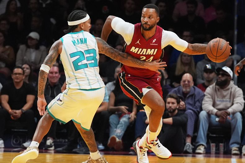Norman Powell (24), del Heat de Miami, toma un balón suelto mientras Tre Mann (23), de los Hornets de Charlotte, defiende durante la primera mitad del juego del baloncesto de la Copa NBA, el viernes 7 de noviembre de 2025, en Miami. (AP Foto/Marta Lavandier)