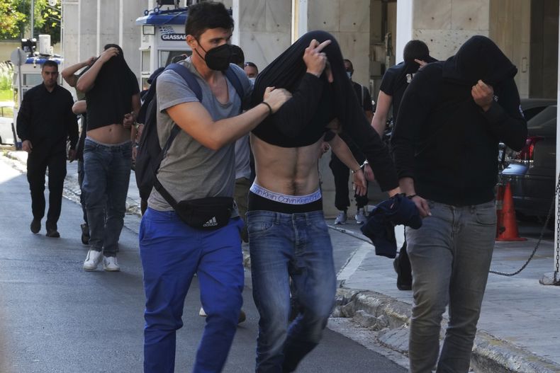 Hinchas de fútbol, en su mayoría de Croacia, se tapan los rostros, al salir del cuartel general de la policía de Atenas, el miércoles 9 de agosto de 2023. (AP Foto/Petros Giannakouris)