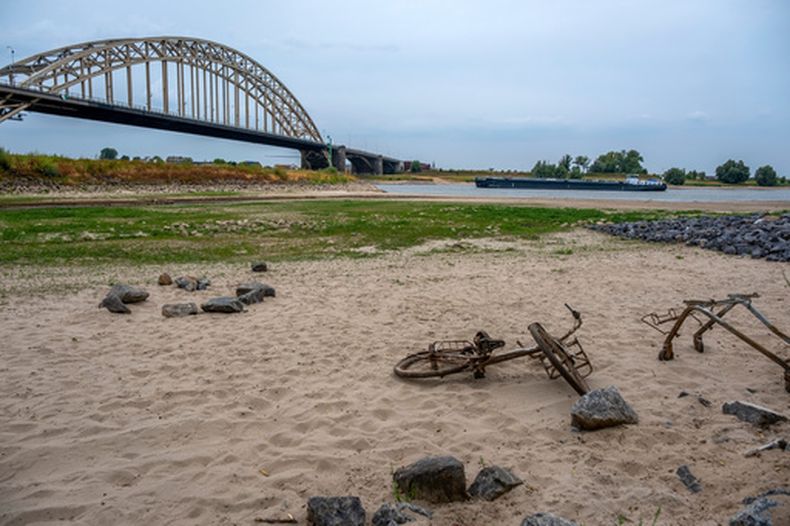 Una bicicleta y un carrito de supermercado oxidados yacen sobre la arena tras retroceder el río Slinge en Varsseveld, Países Bajos, el jueves 30 de julio de 2026, debido a la sequía. (AP Foto/Patrick Post)