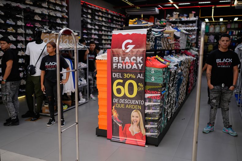 Varios empleados esperan clientes en una zapatería que promueve descuentos del Black Friday en Caracas, Venezuela, el viernes 28 de noviembre de 2025. (AP Foto/Ariana Cubillos)