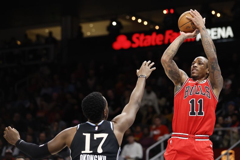En foto del 12 de febrero del 2024, el alero de los Bulls de Chicago DeMar DeRozan lanza el balón sobre el alero de los Hawks de Atlanta Onyeka Okongwu. (AP Foto/Alex Slitz)