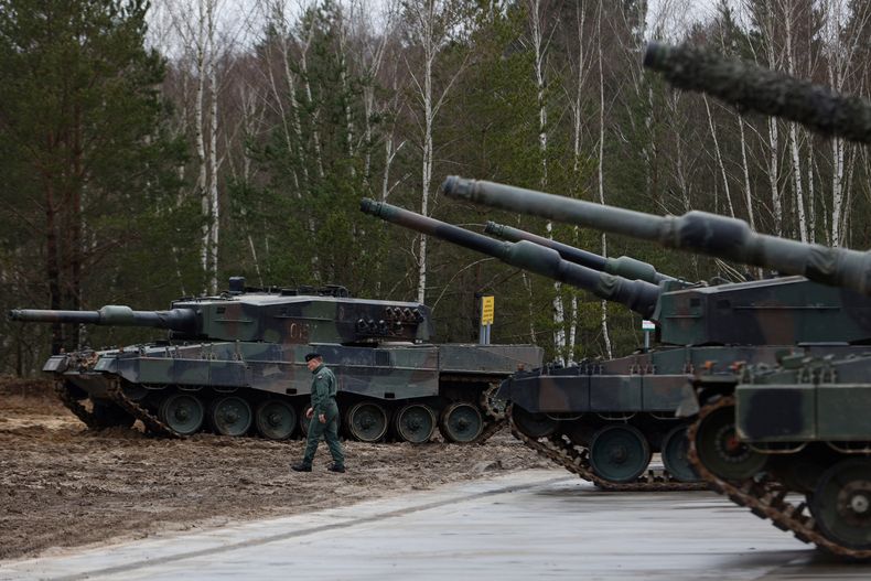 ARCHIVO – Un soldado polaco camina frente a dos tanques Leopard 2 en un entrenamiento en una base militar y campo de pruebas en Swietoszow, Polonia, el lunes 13 de febrero de 2023. (AP Foto/Michal Dyjuk, Archivo)
