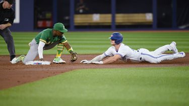 El segunda base de los Atléticos de Oakland, Tony Kemp, a la izquierda, pone out a Matt Chapman (26), de los Azulejos de Toronto, en la segunda entrada del partido en Toronto, el viernes 23 de junio de 2023. (Christopher Katsarov/The Canadian Press vía AP)