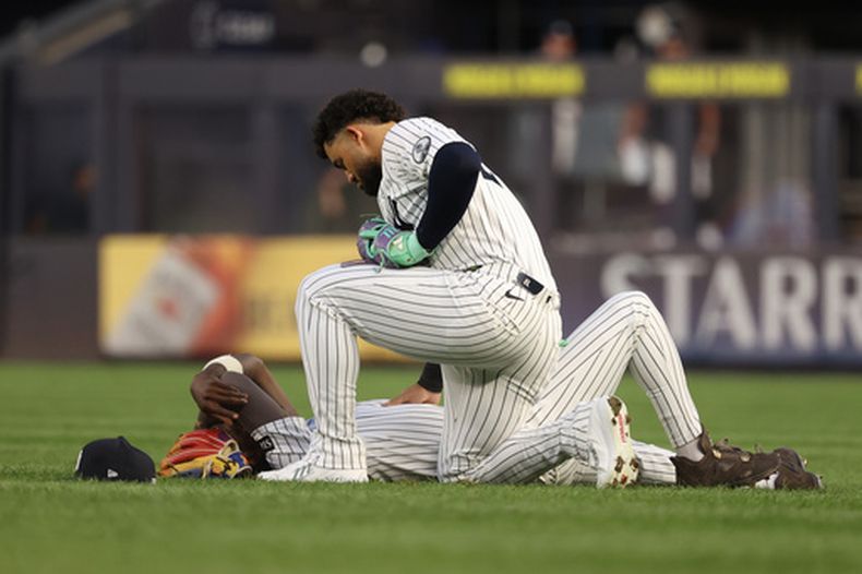 Jasson Domínguez, con una rodilla en el campo, revisa a su compañeros de equipo Jazz Chisholm Jr., tendido, después de que ambos jugadores chocaran mientras perseguían una pelota bateada por Hao-Yu Lee, de los Tigres de Detroit, durante la cuarta entrada del juego de béisbol de Grandes Ligas, el lunes 29 de junio de 2026, en Nueva York. (AP Foto/Pamela Smith)