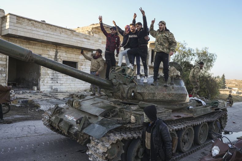 Partidarios de la oposición siria celebran arriba de un tanque de guerra del ejército sirio en el poblado de Maarat al-Numan, al suroeste de Alepo, Siria, el sábado 30 de noviembre de 2024. (AP Foto/Omar Albam)