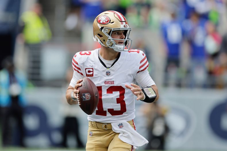 Brock Purdy (13), quarterback de los 49ers de San Fancisco, busca a quien lanzarle el balón durante la primera mitad del partido de la NFL en contra de los Seahawks de Seattle, el domingo 7 de septiembre de 2025, en Seattle. (AP Foto/John Froschauer)