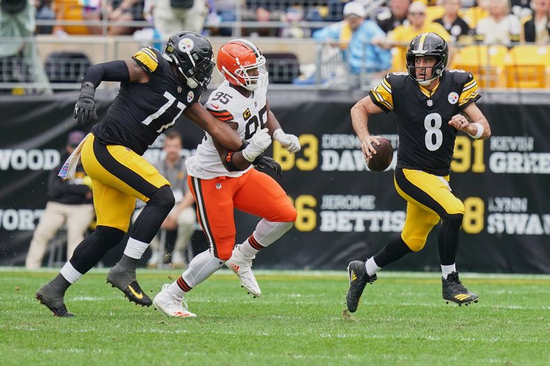 El quarterback de los Steelers de Pittsburgh, Aaron Rodgers (8), escapa mientras es perseguido por el defensive end de los Browns de Cleveland, Myles Garrett (95), en la primera mitad de un juego de fútbol americano de la NFL en Pittsburgh, el domingo 12 de octubre de 2025. (AP Photo/Matt Freed)
