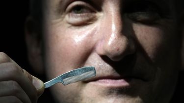Un empleado de Sothebys muestra un peine para bigote de los artículos personales de Freddie Mercury en las salas de subastas de Sothebys en Londres, el jueves 3 de agosto de 2023. Más de 1.400 artículos personales de Freddie Mercury, incluidos sus extravagantes vestuarios, borradores escritos a mano de Bohemian Rhapsody y el piano de media cola que usó para componer grandes éxitos de Queen, se exhibirán en la casa de subastas Sothebys Londres antes de su venta. (Foto AP/Kirsty Wigglesworth)