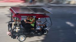 Varias personas viajan en un triciclo eléctrico equipado con un panel solar en La Habana, Cuba, el viernes 10 de julio de 2026. (AP Foto/Ramón Espinosa)
