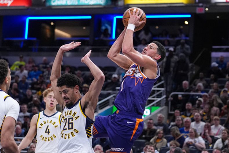 Devin Booker, de los Suns de Phoenix, dispara frente a Ben Sheppard, de los Pacers de Indiana, en el encuentro del jueves 12 de marzo de 2026 (AP Foto/Michael Conroy)