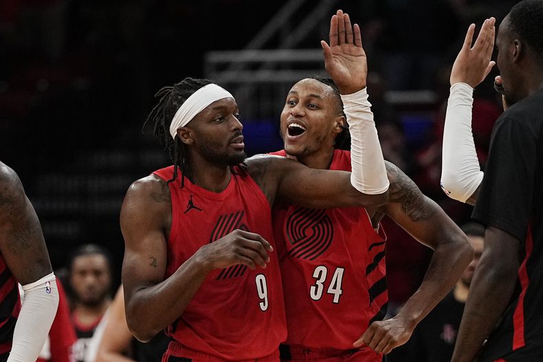 El alero Jerami Grant, de los Trail Blazers de Portland, es felicitado por Jabari Walker tras atinar un triple para forzar la prórroga ante los Rockets de Houston, el miércoles 24 de enero de 2024 (AP Foto/Kevin M. Cox)