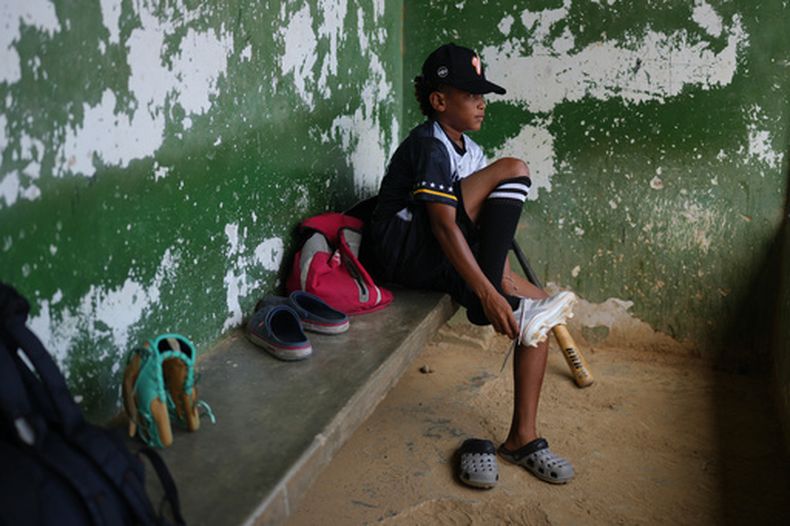 Yeferson Seijas se pone sus zapatos deportivos para un entrenamiento de béisbol en La Guaira, Venezuela, el sábado 11 de julio de 2026, después de que los sismos dejaran a su familia sin hogar, y de que algunos de los niños con los que creció jugando acabaran lesionados, huérfanos, muertos o desaparecidos. (AP Foto/Ariana Cubillos)
