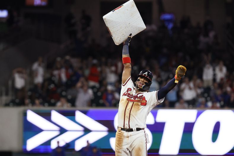Ronald Acuña Jr. (13), de los Bravos de Atlanta, sostiene la almohadilla en lo alto después de un robo de base en contra de los Cachorros de Chicago durante la 10ma entrada del juego de béisbol, el miércoles 27 de septiembre de 2023, en Atlanta. Fue el 70mo robo de Acuña en la temporada. (Miguel Martinez/Atlanta Journal-Constitution vía AP)