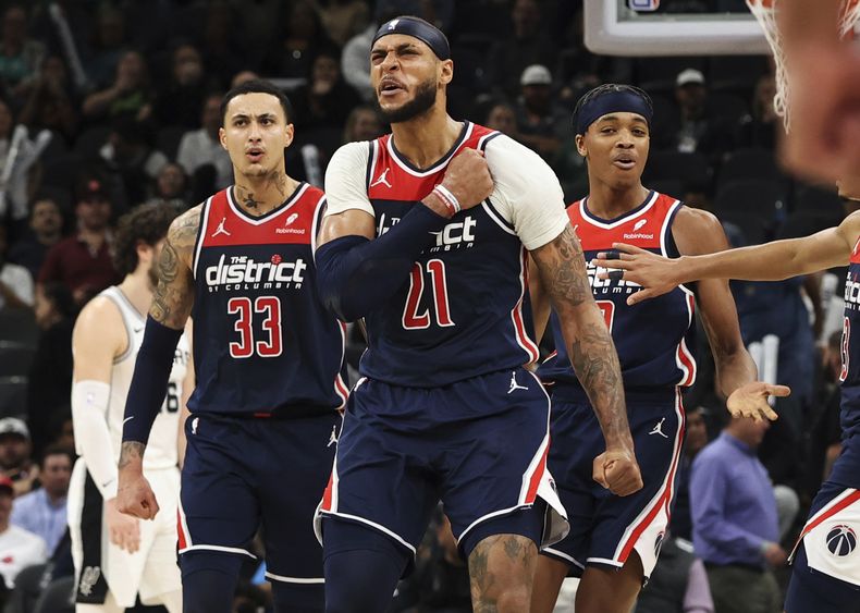 Daniel Gafford (21), de los Wizards de Washington, reacciona al lado de sus compañeros Kyle Kuzma (33) y Bilal Coulibaly, derecha, después de una canasta en contra de los Spurs de San Antonio durante la segunda mitad del juego de baloncesto de la NBA, en San Antonio, el lunes 29 de enero de 2024. (AP Foto/Kin Man Hui)