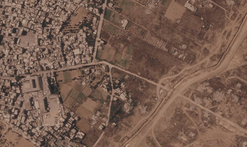 Esta imagen por satélite de Planet Labs PBC muestra un tramo de una barrera de tierra construida por el ejército israelí, desde el lado derecho de la imagen y hacia abajo, en el centro de la Franja de Gaza, el 1 de julio de 2026. A la izquierda se ve el campo de refugiados de Maghazi, y al otro lado casas demolidas por el ejército. (Planet Labs PBC via AP)