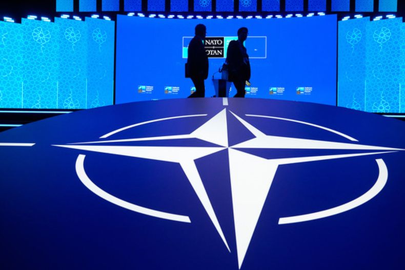 Dos hombres pasan junto al logo de la OTAN durante el Foro de Industria de Defensa en la cumbre de Ankara, Turquía, el martes 7 de julio de 2026. (AP Foto/Hussein Malla)
