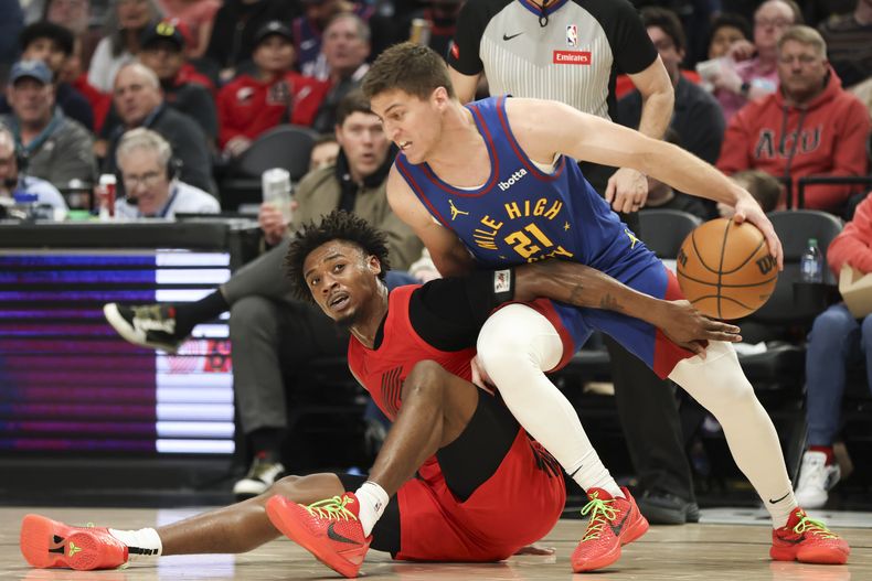 El jugador de los Trail Blazers de Portland Ashton Hagans, a la izquierda, y el jugador de los Nuggets de Denver Collin Gillespie (21) luchan por un balón perdido en la segunda mitad de su juego de NBA el sábado 23 de marzo de 2024 en Portland, Oregon. (AP Foto/Amanda Loman)
