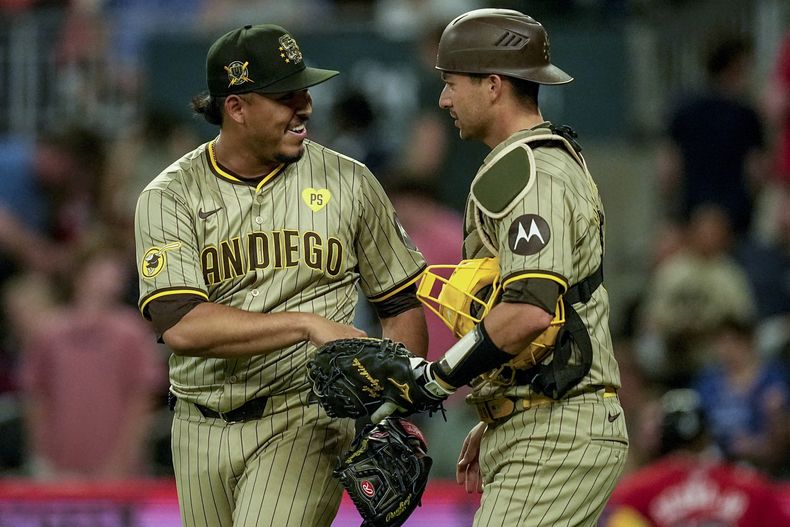 Jeremiah Estrada, izquierda, de los Padres de San Diego, celebra con Kyle Higashioka (20) la victoria después de derrotar en juego de béisbol a los Bravos de Atlanta, el viernes 17 de mayo de 2024, en Atlanta. Los Padres ganaron 3-1. (AP Foto/Mike Stewart)