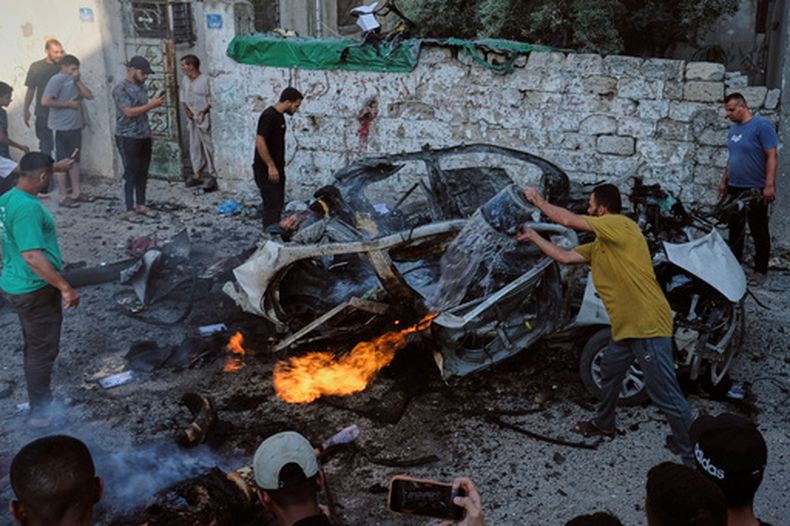 NOTA DEL EDITOR: CONTENIDO GRÁFICO - Palestinos intentan apagar un coche en llamas tras un ataque militar israelí, el domingo 2 de agosto de 2026, en la ciudad de Gaza. (AP Foto/Jehad Alshrafi)