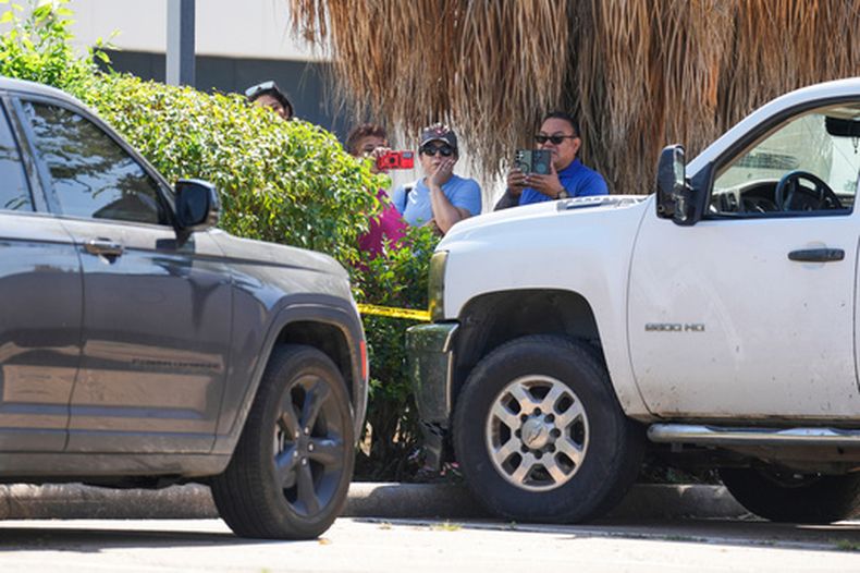 Varias personas observan mientras policías del condado Harris trabajan en el lugar cerca de dos vehículos implicados después de que un hombre fuera golpeado por un vehículo de agentes del Servicio de Inmigración y Control de Aduanas (ICE, por sus siglas en inglés), durante una operación de aplicación de las leyes migratorias en el noroeste de Houston, el sábado 10 de octubre de 2026. (Jason Fochtman/Houston Chronicle vía AP)