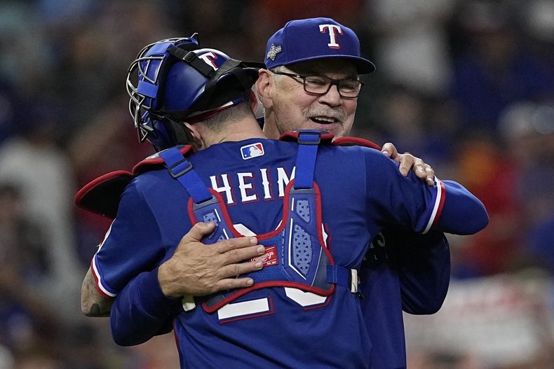Bruce Bochy, manager de los Rangers de Texas, abraza a Jonah Heim, tras el séptimo juego de la Serie de Campeonato de la Liga Americana ante los Astros de Houston, el lunes 23 de octubre de 2023 (AP Foto/David J. Phillip)