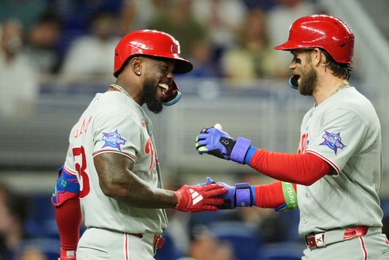 Bryce Harper, derecha, de los Filis de Filadelfia, celebra con Adolis Garcia después de batear un jonrón durante la tercera entrada del juego de béisbol en contra de los Marlins de Miami, el lunes 4 de mayo de 2026, en Miami. (AP Foto/Rebecca Blackwell)