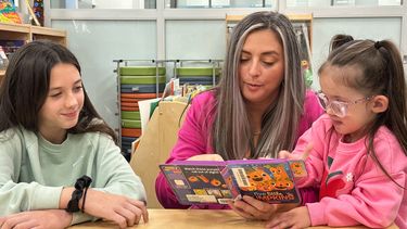 Christina Middleton, en el centro, lee con sus hijas, Tiffanie Hiatt-Calhoon, de 11 años, a la izquierda, y Mikaylie Middleton, de 3 años, a la derecha, en el Centro de Educación Infantil Great Beginnings, el jueves 23 de octubre de 2025, en Lees Summit, Missouri. (AP Foto/Nick Ingram)
