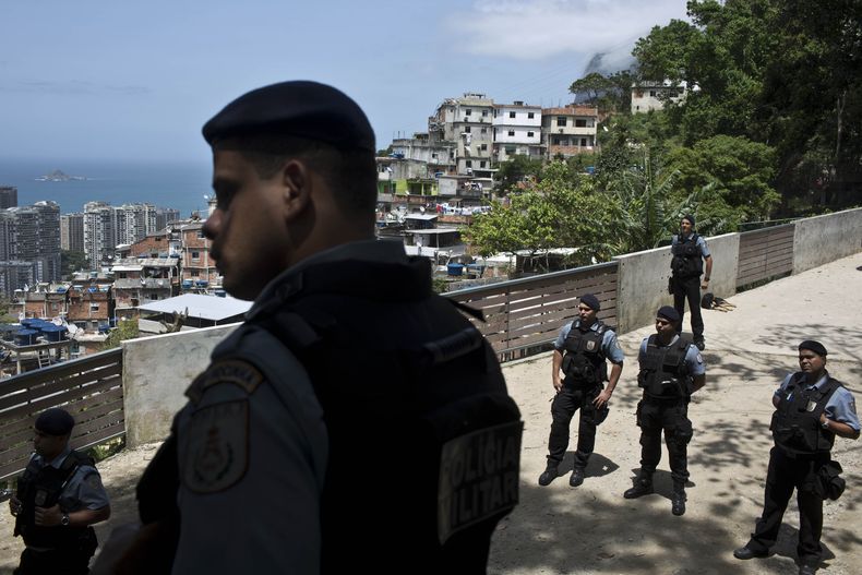 Agentes policiales observan a manifestantes que exigen saber el paradero de los restos mortales del alba&ntilde;il Amarildo de Souza, que desapareci&oacute; a mediados de junio mientras estaba custodiado por la polic&iacute;a, en R&iacute;o de Janeiro, Br